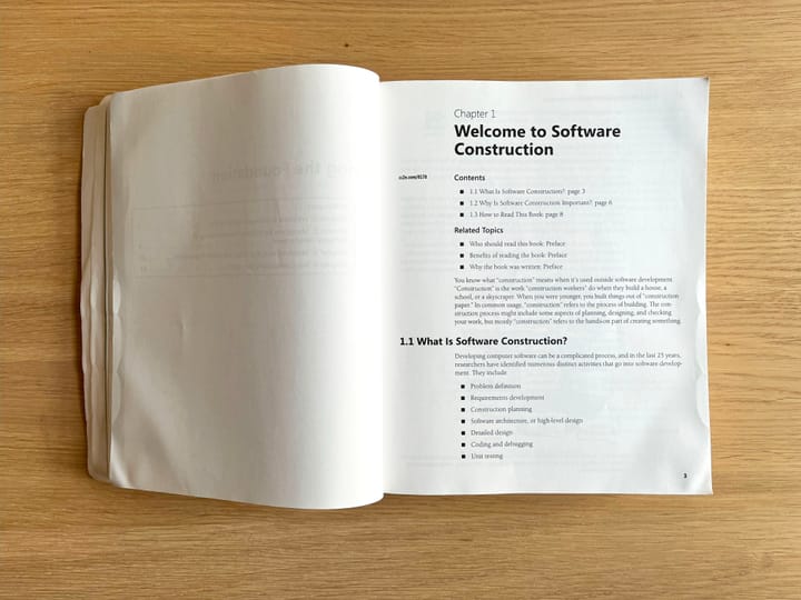 Code Complete lying on a wooden table, open to Chapter one: "Welcome to Software Construction"